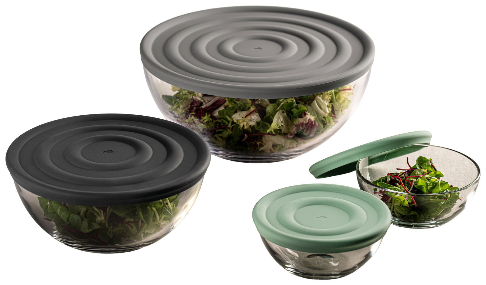 Drei Glasschalen mit Deckeln in verschiedenen Farben, gefüllt mit frischem Salat, aus einer seitlichen Perspektive fotografiert.
