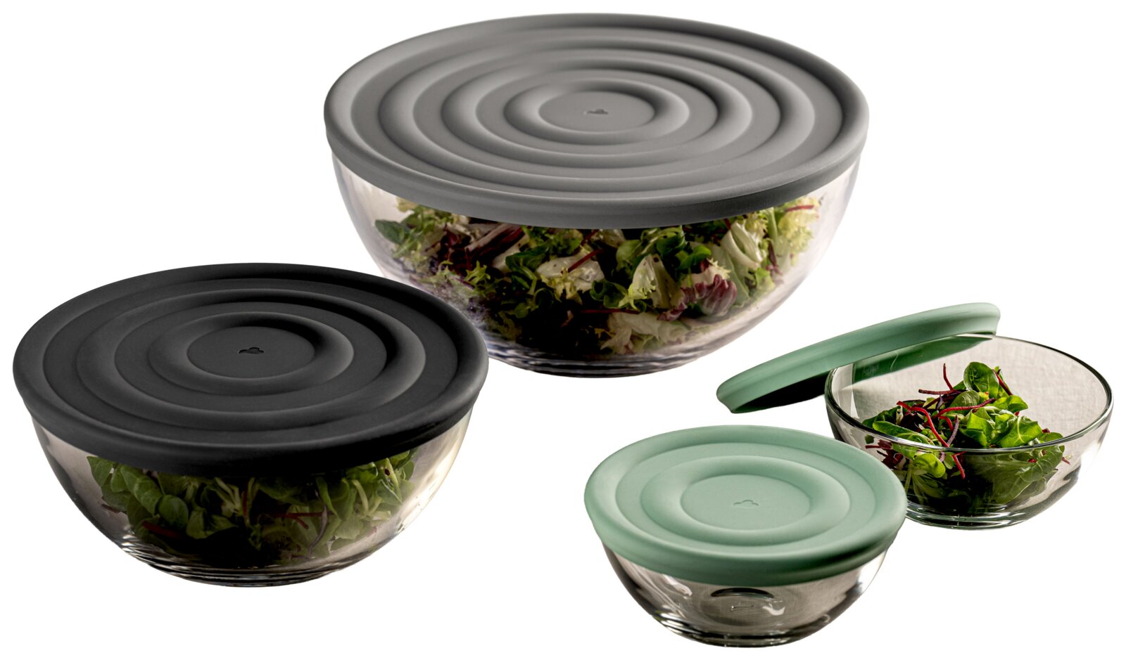 Drei Glasschalen mit Deckeln in verschiedenen Farben, gefüllt mit frischem Salat, aus einer seitlichen Perspektive fotografiert.