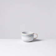 Weiße Keramik-Kaffeetasse mit hellblau-grauem, marmoriertem Streifen und Henkel rechts, freigestellt vor hellem Hintergrund, frontal in leichter Seitenansicht