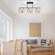 Moderne Deckenleuchte mit drei goldenen Ringen in einem stilvollen Wohnzimmer, seitliche Perspektive.