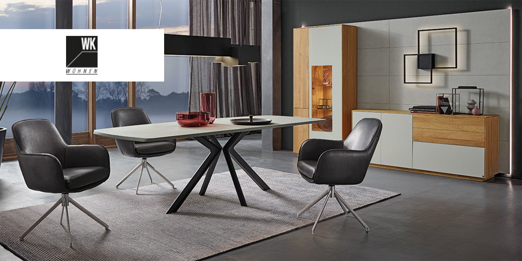 Ein elegantes Esszimmer mit modernem Tisch, schwarzen Ledersesseln und stilvoll beleuchteter Wand.