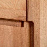Close-up detail van een houten meubelverbinding met zichtbaar houtnerfpatroon en strakke afwerking, gefotografeerd vanuit een schuine zijaanzichtperspectief.