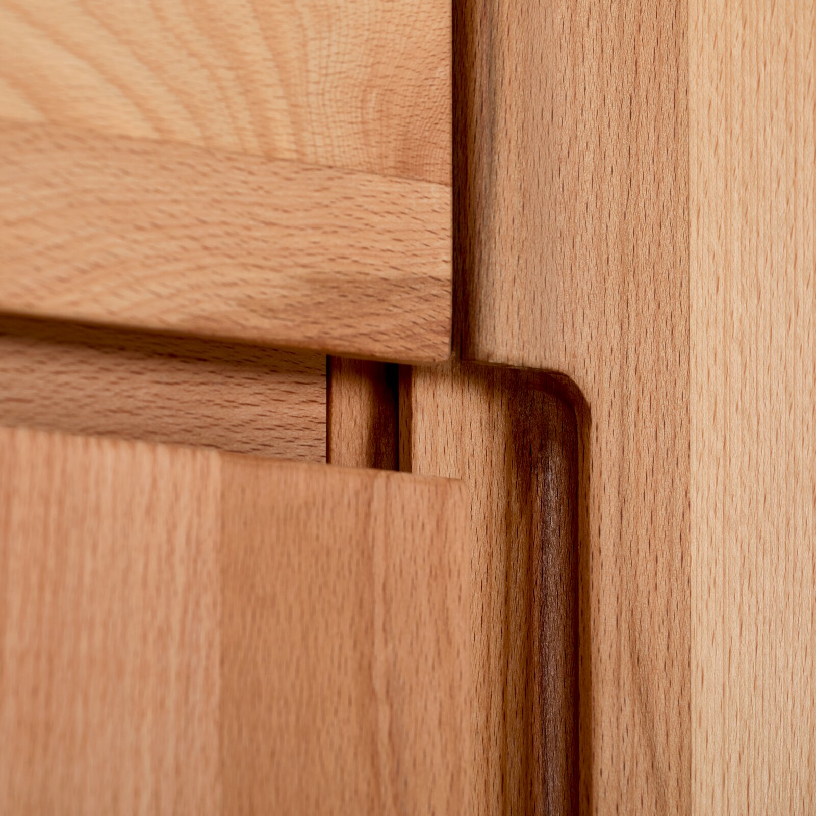 Close-up detail van een houten meubelverbinding met zichtbaar houtnerfpatroon en strakke afwerking, gefotografeerd vanuit een schuine zijaanzichtperspectief.
