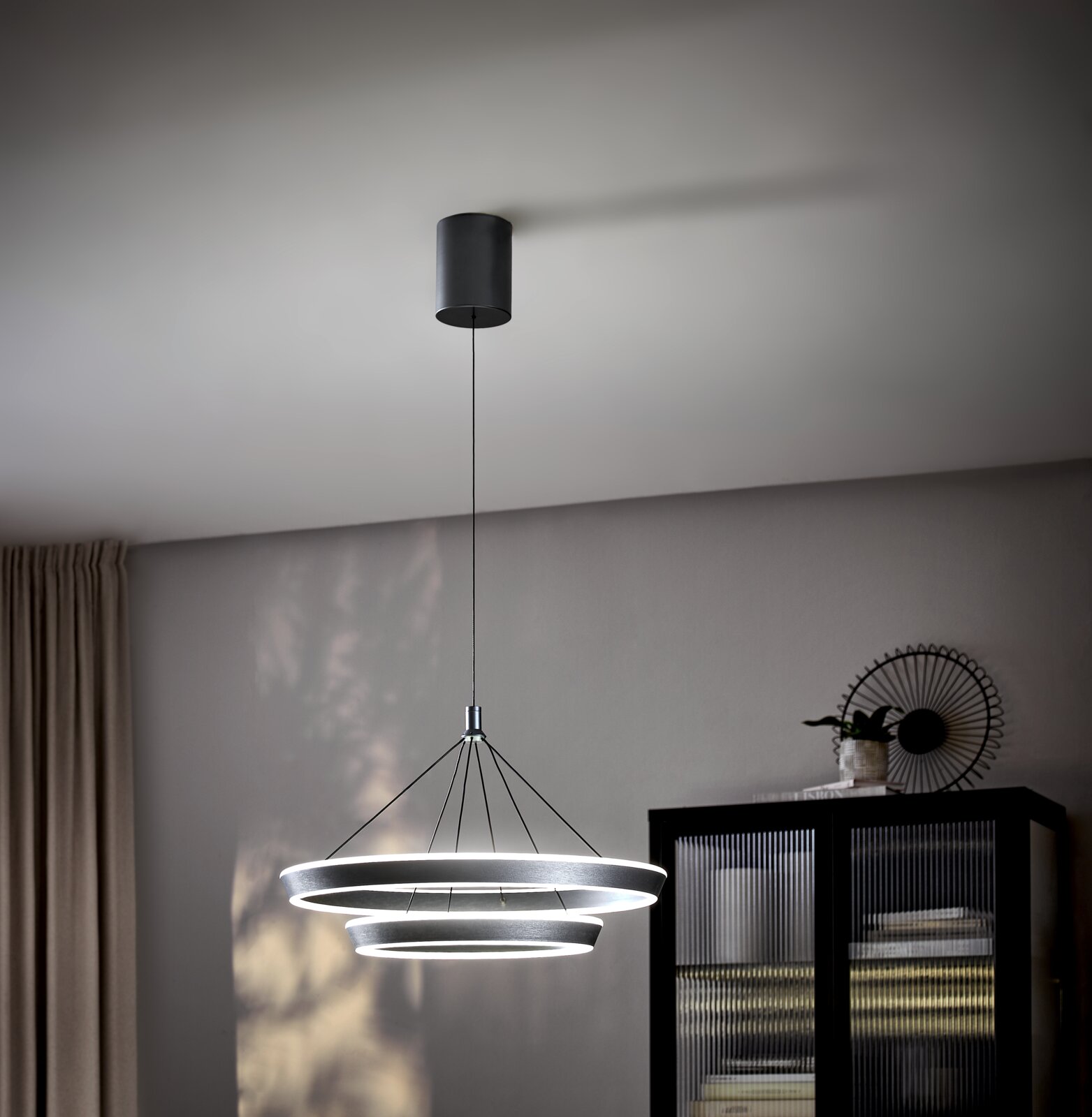 Moderne LED-Hängeleuchte mit drei ringförmigen Leuchtelementen, von der Decke hängend, seitliche Perspektive