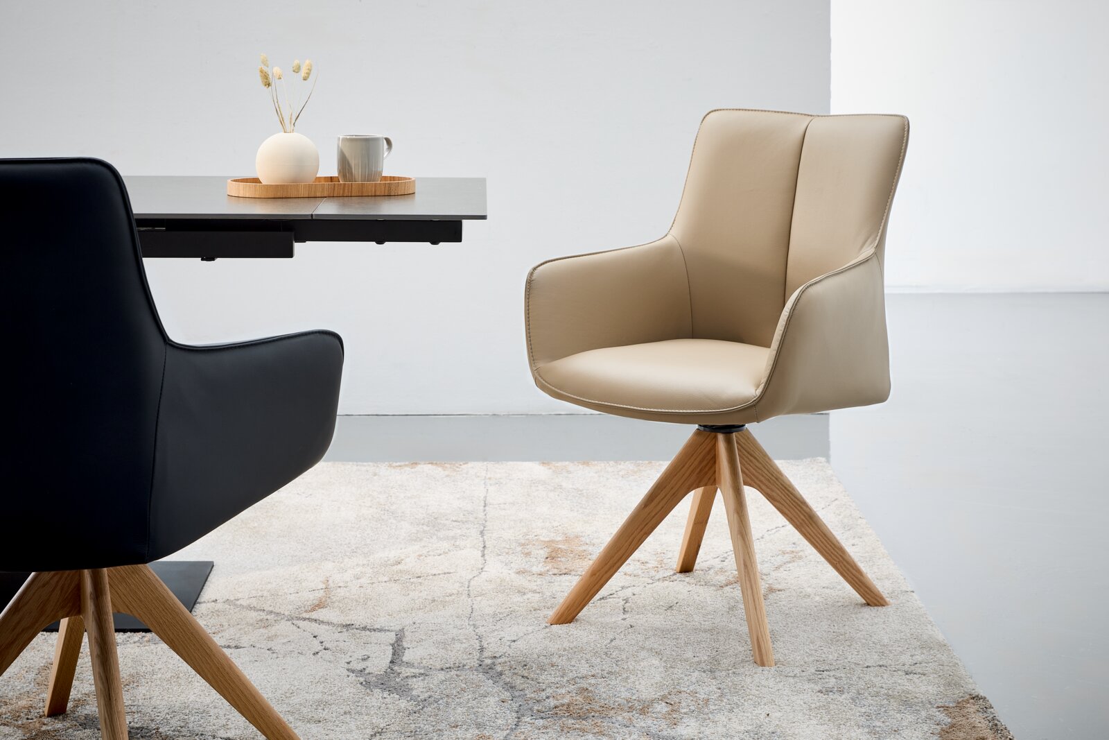 Beige fauteuil met houten poten, zijaanzicht, naast een tafel met decoratie.