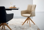 Beige fauteuil met houten poten, zijaanzicht, naast een tafel met decoratie.
