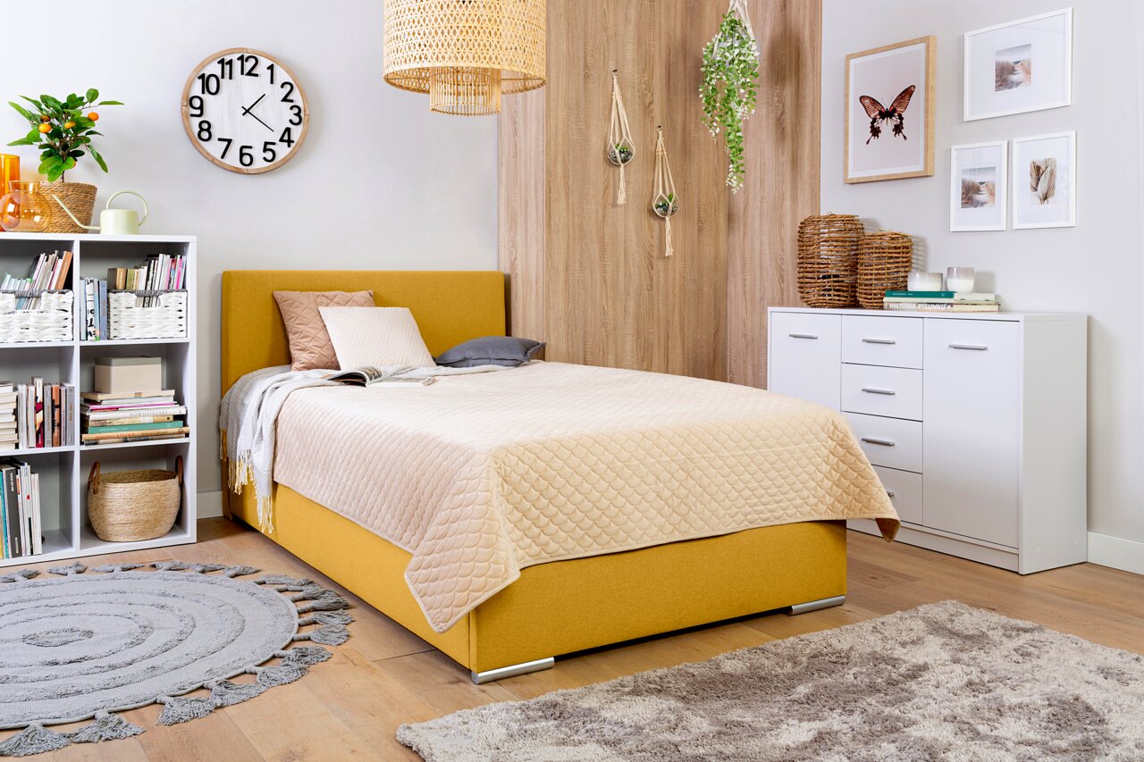 Een gezellige slaapkamer met een geel boxbed, omringd door stijlvolle decoratie en meubels, gefotografeerd vanuit een zijaanzicht.