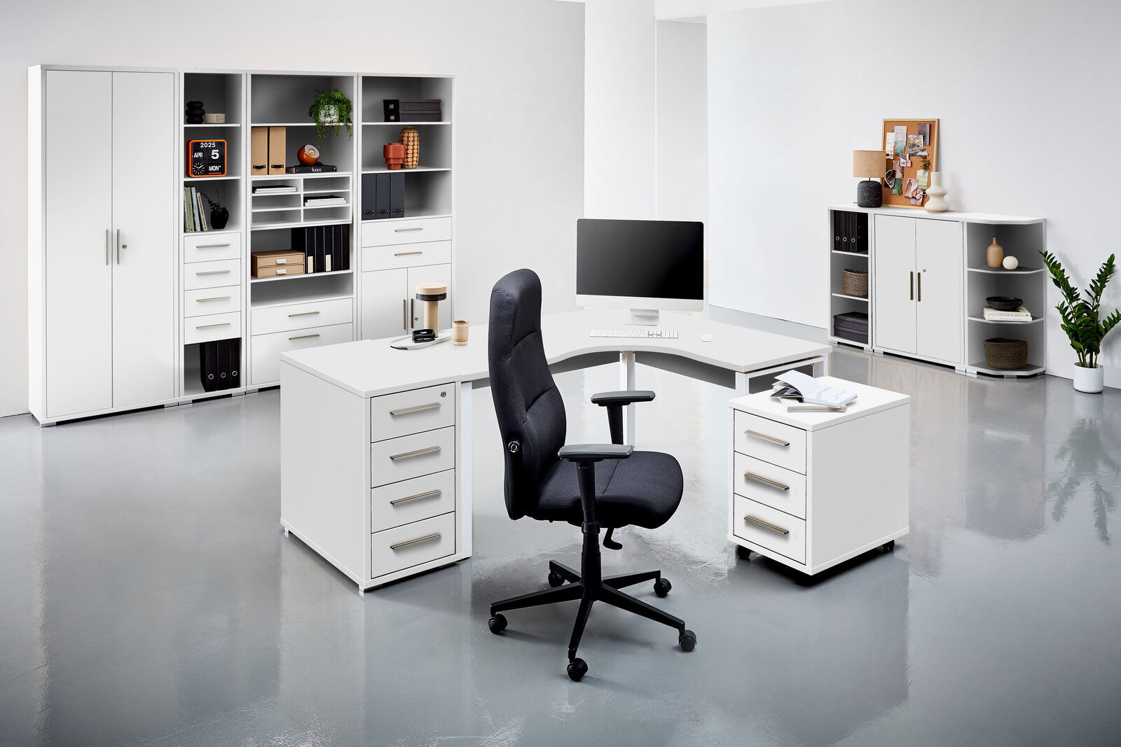 Moderne Büroumgebung mit weißen Schreibtischen, Regalen und einem schwarzen Bürostuhl, aus der Perspektive eines Betrachters im Raum.