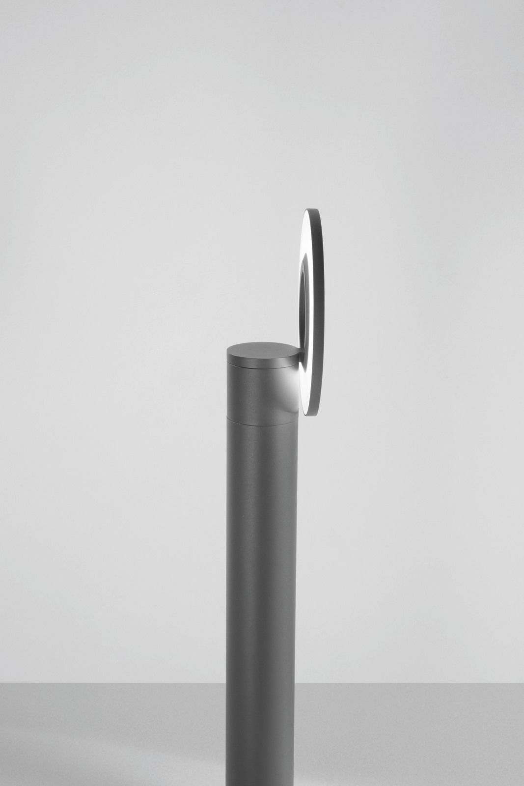 Seitenansicht einer modernen LED-Pollerleuchte mit rundem Leuchtelement auf einem schlanken, zylindrischen Sockel.