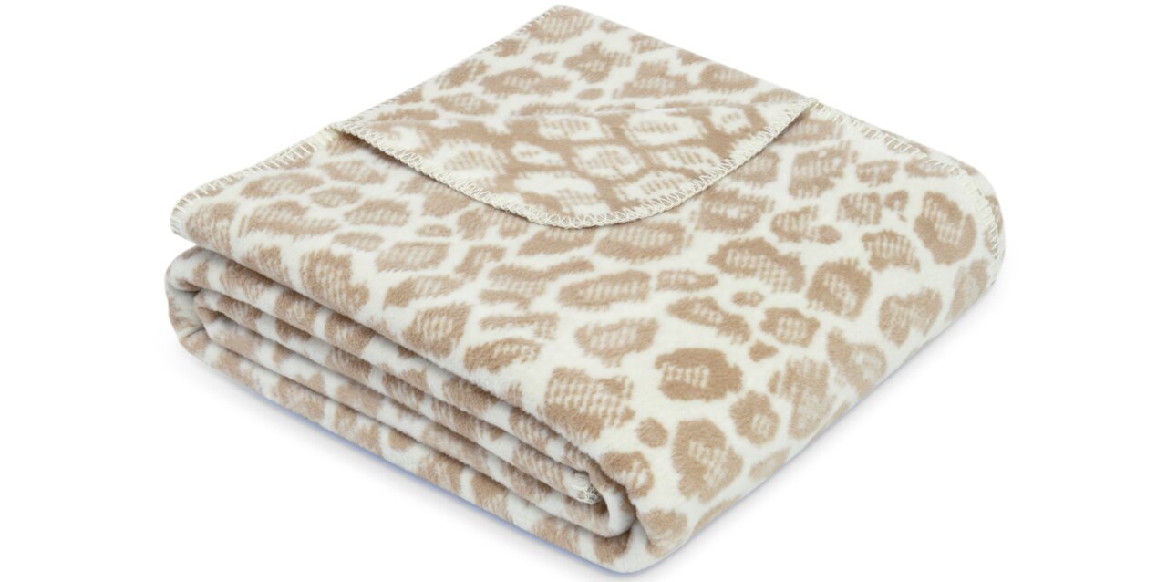 Gevouwen beige-witte woondeken met luipaardpatroon, zijaanzicht
