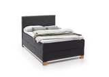 Boxspringbett in dunklem Stoff mit hohem Kopfteil, seitliche Perspektive