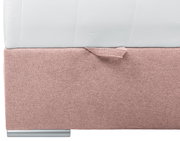 Close-up van een boxspring met roze stoffen bekleding en zilveren poten, gezien vanaf de zijkant
