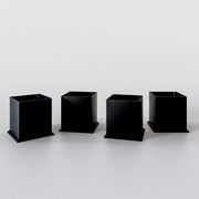 Vier schwarze, quadratische Sockel aus Metall, frontal betrachtet, auf einer hellen Oberfläche.