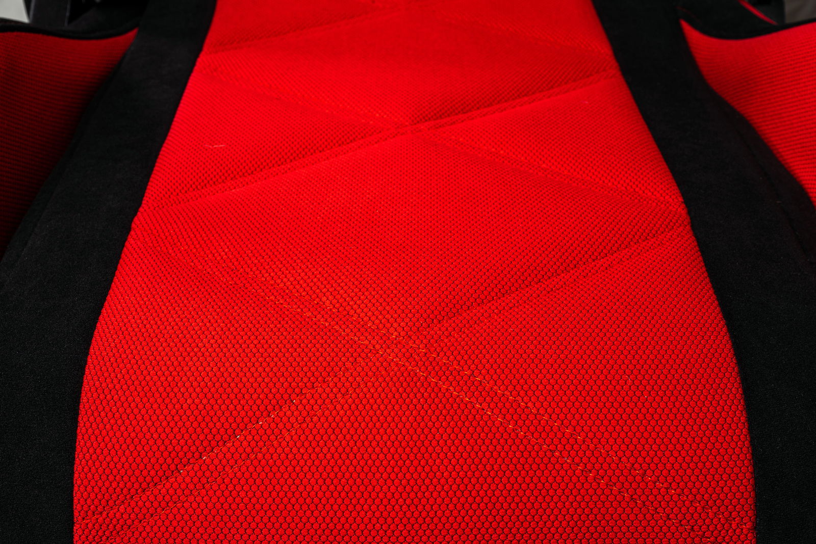 Nahaufnahme eines roten Gaming-Stuhls mit schwarzem Rand, aus der Vogelperspektive fotografiert.