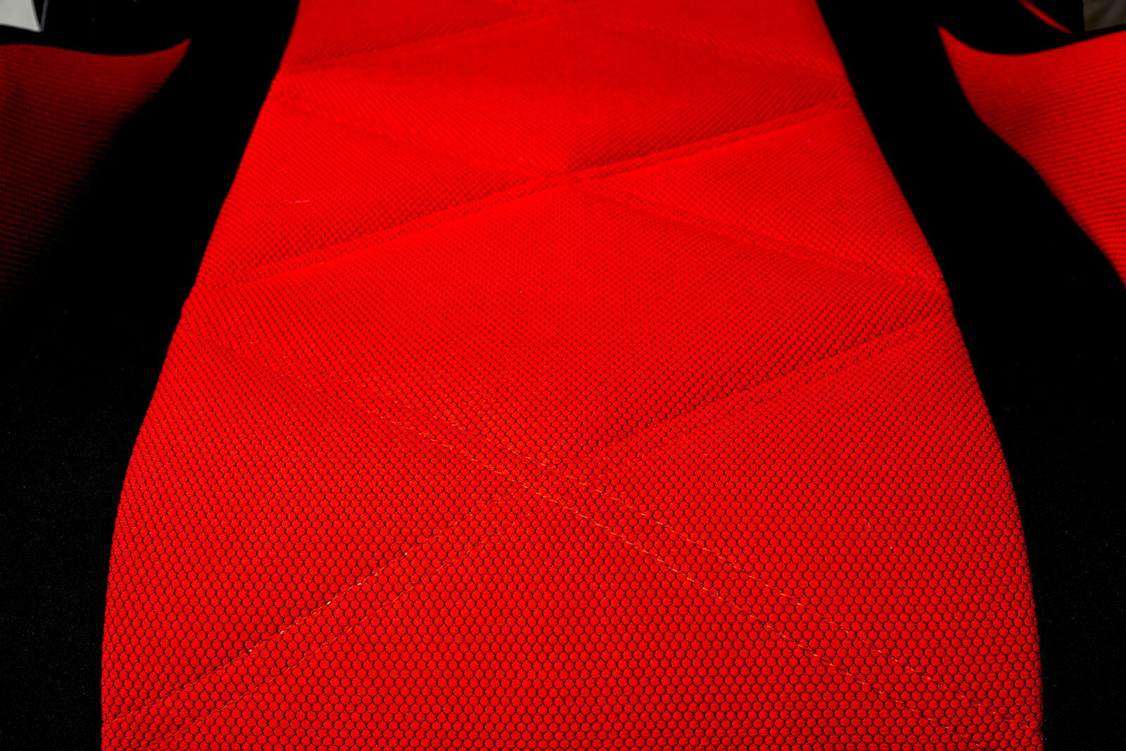 Nahaufnahme eines roten Gaming-Stuhls mit schwarzem Rand, aus der Vogelperspektive fotografiert.