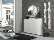 Modern wit dressoir in de hal voor een grijze stenen muur, met een ronde spiegel en decoratie op de plank; schuin vooraanzicht.