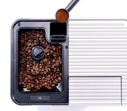 Draufsicht auf einen Kaffeevollautomaten mit Kaffeebohnenbehälter und Kaffeepulver im Messlöffel.