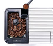 Draufsicht auf einen Kaffeevollautomaten mit Kaffeebohnenbehälter und Kaffeepulver im Messlöffel.