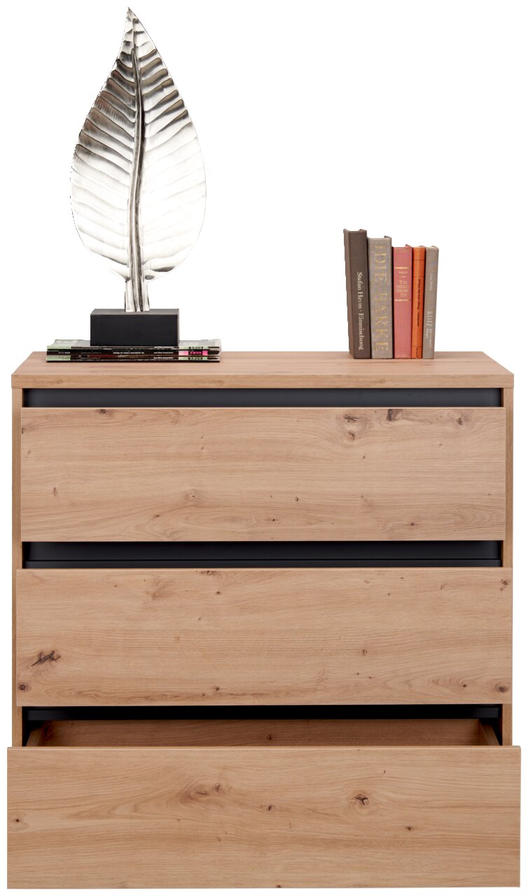 Kommode aus Holz mit drei Schubladen, eine davon leicht geöffnet, dekoriert mit einer silbernen Blattskulptur und Büchern, Frontalansicht.