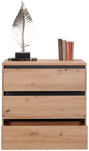 Kommode aus Holz mit drei Schubladen, eine davon leicht geöffnet, dekoriert mit einer silbernen Blattskulptur und Büchern, Frontalansicht.