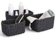 Dreiteiliges Aufbewahrungskorb-Set in Schwarz, gefüllt mit Pflegeprodukten und Handtüchern, aus einer leicht erhöhten Perspektive fotografiert.