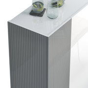 Nahaufnahme eines modernen Schuhschranks mit geriffelter Oberfläche und glänzender weißer Oberseite, darauf stehen Gläser und ein Tuch.