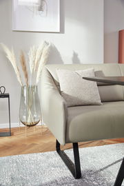 Moderne Sitzbank in einem stilvollen Wohnzimmer, seitliche Perspektive, mit Kissen und dekorativer Vase im Hintergrund.