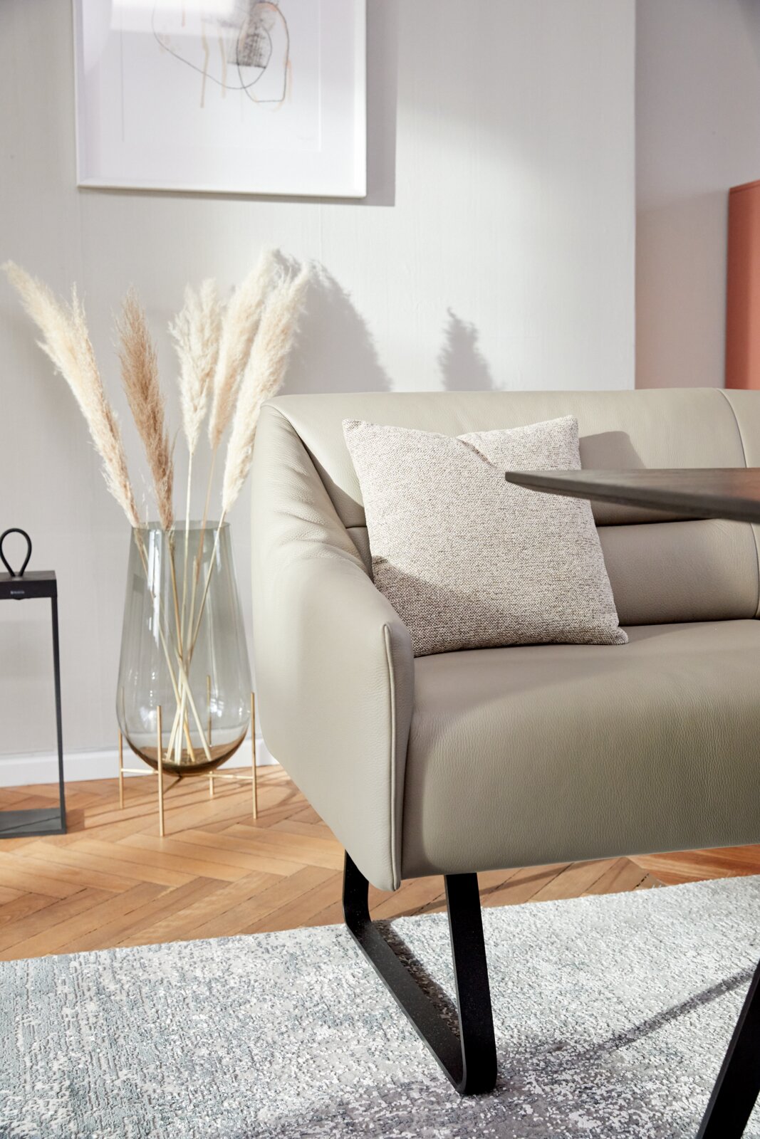 Moderne bank in een stijlvolle woonkamer, gezien vanaf de zijkant, met kussens en een decoratieve vaas op de achtergrond.
