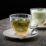 Glas-Tasse mit frischem Minztee auf Untertasse, seitliche Perspektive