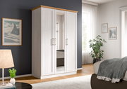 Weißer Kleiderschrank mit drei Türen und mittiger Spiegeltür, Holz-Abdeckplatte und Metallgriffen, in einem hellen Schlafzimmer – Frontansicht leicht schräg von links.