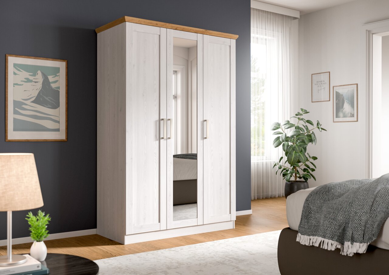 Weißer Kleiderschrank mit drei Türen und mittiger Spiegeltür, Holz-Abdeckplatte und Metallgriffen, in einem hellen Schlafzimmer – Frontansicht leicht schräg von links.