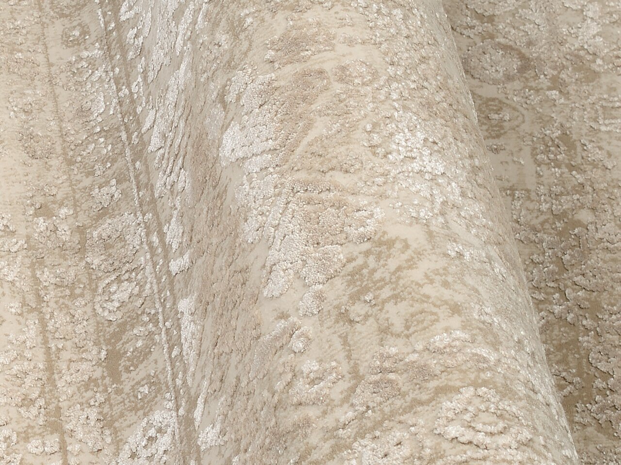 Nahaufnahme eines Designer-Teppichs mit beige-weißen Mustern, aus seitlicher Perspektive aufgenommen.