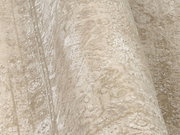 Nahaufnahme eines Designer-Teppichs mit beige-weißen Mustern, aus seitlicher Perspektive aufgenommen.