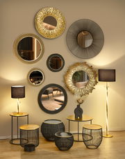 Wand mit mehreren runden Spiegeln in verschiedenen Designs, darunter ein goldener Spiegel mit strukturiertem Rahmen. Perspektive: Frontalansicht.