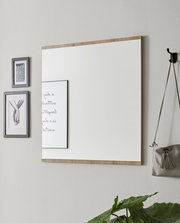 Rechteckiger Wandspiegel mit Holzrahmen, seitliche Perspektive, neben dekorativen Bildern und einer Tasche an der Wand.