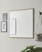 Rechteckiger Wandspiegel mit Holzrahmen, seitliche Perspektive, neben dekorativen Bildern und einer Tasche an der Wand.