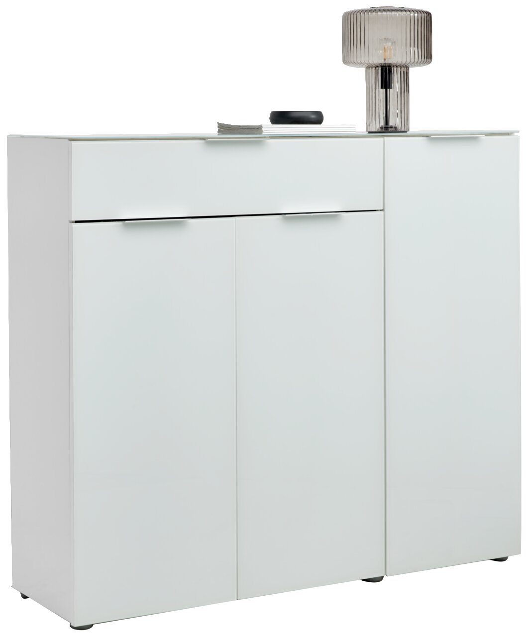 Voleo XL-Schuhschrank MALIN Moderner XL-Schuhschrank in Weiß mit drei Türen und einer Schublade, seitliche Perspektive, dekoriert mit einer Lampe und Accessoires auf der Oberseite.