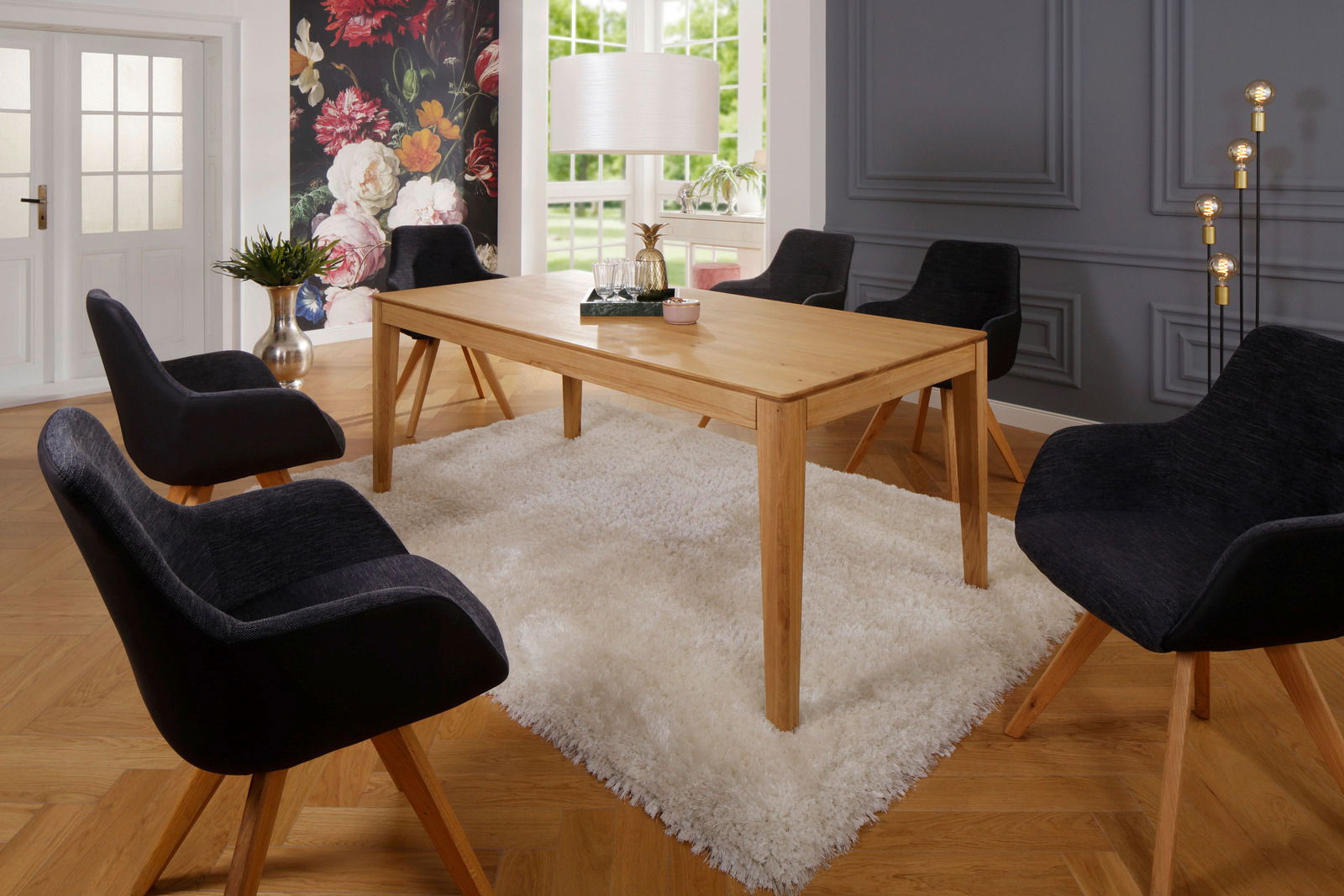 Moderner Esstisch aus Holz in einem stilvollen Esszimmer mit schwarzem Stuhl-Set, Teppich und dekorativer Wand im Hintergrund, seitliche Perspektive.