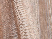 Nahaufnahme eines Designer-Teppichs mit geometrischem Muster in Beige- und Brauntönen, aus seitlicher Perspektive aufgenommen.