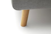 Close-up van een houten bedpoot met grijze stoffen bekleding, gezien vanaf de zijkant