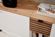 Nahaufnahme eines modernen Garderoben-Sets mit weißem und holzfarbenem Finish, von oben betrachtet. Auf der Oberfläche befinden sich Dekorationsgegenstände und eine Brille.