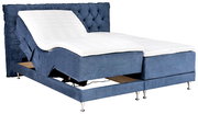Blaues elektrisches Boxspringbett mit gepolstertem, gestepptem Kopfteil und verstellbarer Liegefläche, schräg von vorne links in Seitenansicht fotografiert