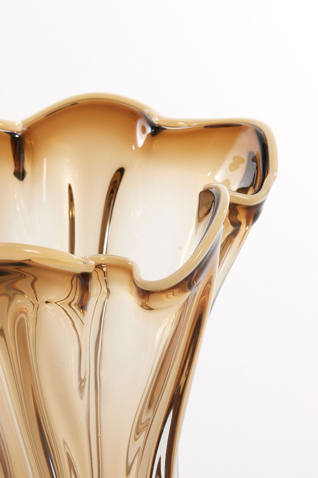 Nahaufnahme einer eleganten, wellenförmigen Vase aus braunem Glas mit geschwungenem Rand, von oben betrachtet.