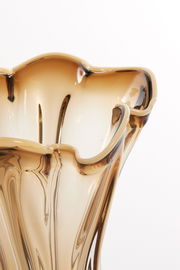 Nahaufnahme einer eleganten, wellenförmigen Vase aus braunem Glas mit geschwungenem Rand, von oben betrachtet.