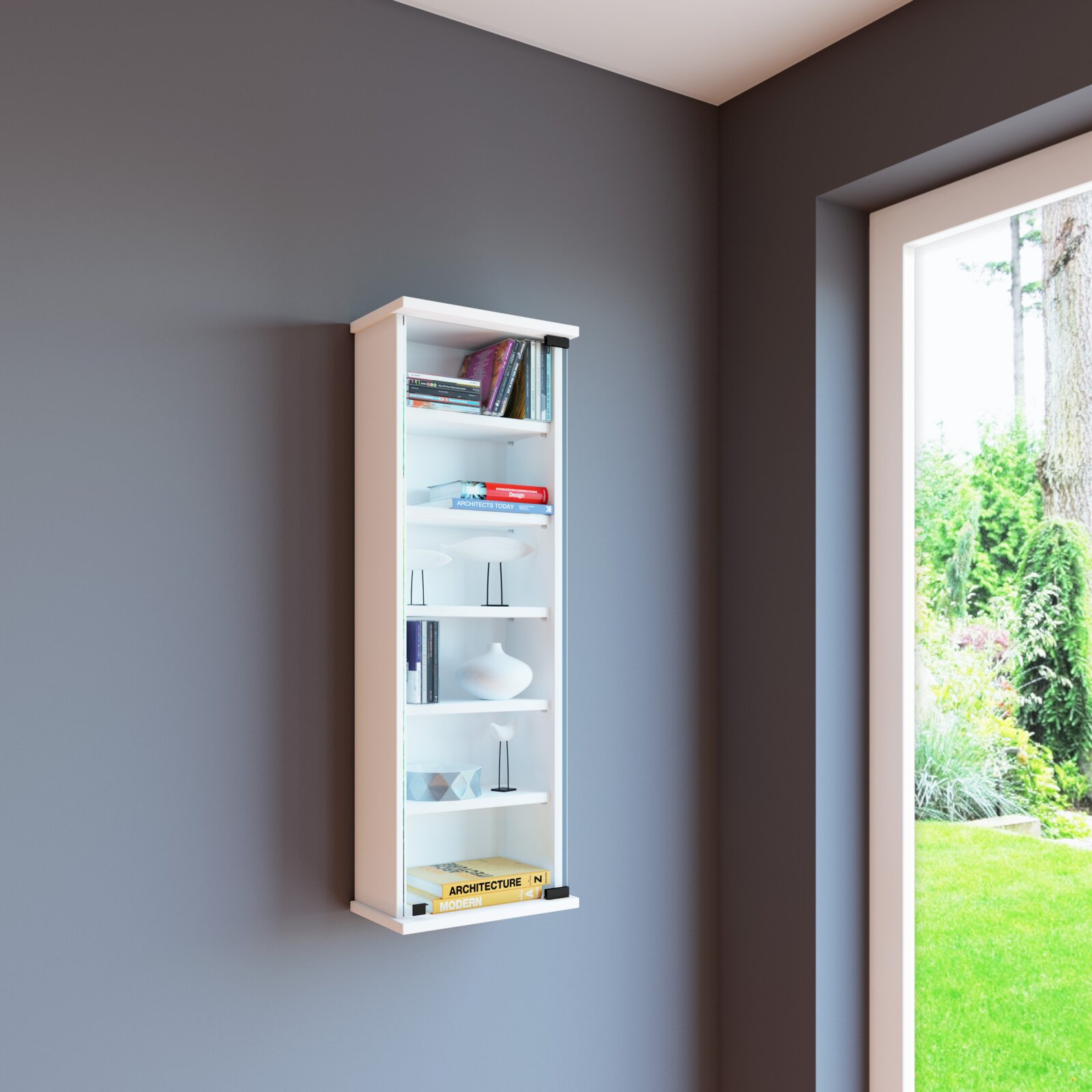Schmales weißes Wandregal mit mehreren Ablageböden, bestückt mit Büchern und Dekoration, an einer dunkelgrauen Wand neben einem Fenster, perspektivisch leicht von rechts vorne aufgenommen.