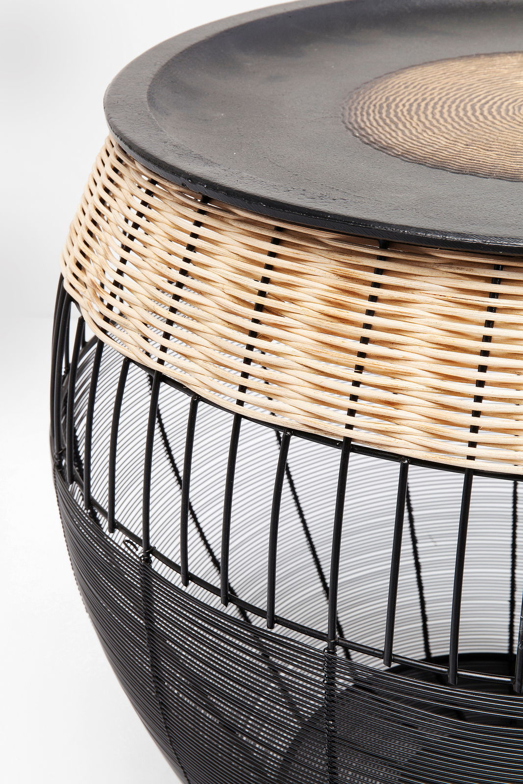 Nahaufnahme eines modernen Beistelltisches mit schwarzem Metallgestell und geflochtenem Rattan-Element, seitliche Perspektive.