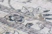 Nahaufnahme eines Luxor Living Teppichs der Serie PRIMA mit floralem Muster in sanften Beige- und Grautönen, perspektivisch schräg von der Seite aufgenommen.