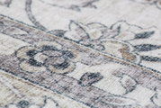 Nahaufnahme eines Luxor Living Teppichs der Serie PRIMA mit floralem Muster in sanften Beige- und Grautönen, perspektivisch schräg von der Seite aufgenommen.