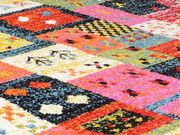 Nahaufnahme eines bunten Designer-Teppichs mit geometrischen Mustern in lebendigen Farben wie Rot, Pink, Gelb und Blau.