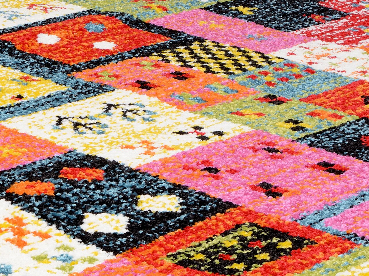 Nahaufnahme eines bunten Designer-Teppichs mit geometrischen Mustern in lebendigen Farben wie Rot, Pink, Gelb und Blau.